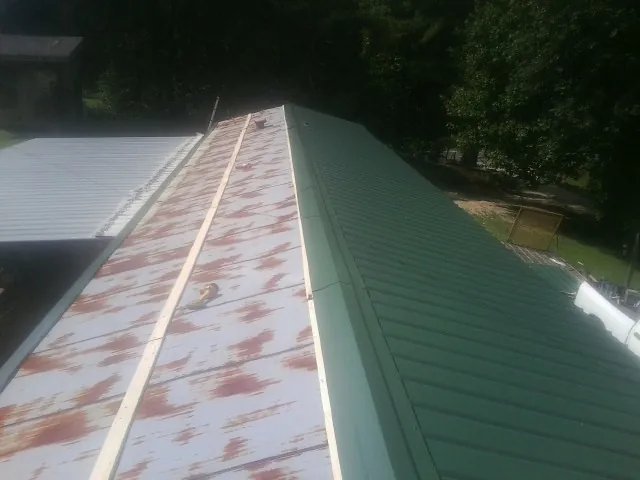 Old rusted panels beside newly installed green metal roofing — Wind Damage Roof Repair by Roofing Brothers in Tuckerton