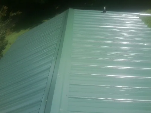 New green metal panels meeting at the ridge of a roof — Flat Roof Repair work by our crew in Tuckerton
