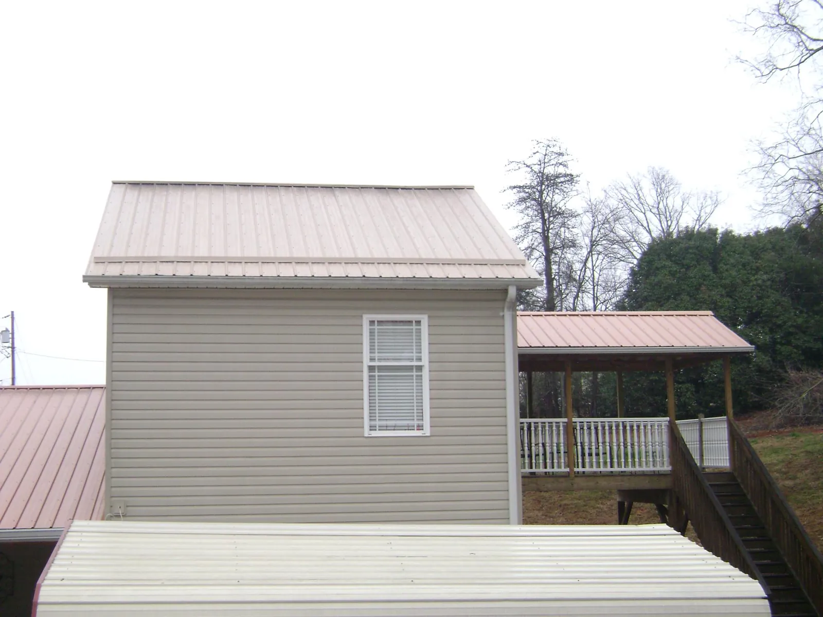 Tan metal roofs on a two story addition and attached porch, from a Roof Replacement job in Tuckerton
