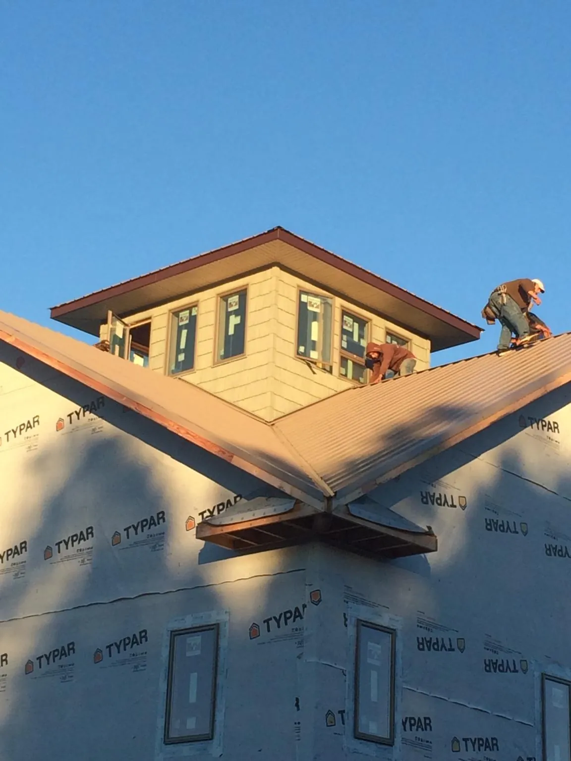 Roofers working around a rooftop cupola on a new metal roof at sunset — Roof Waterproofing in Tuckerton by Roofing Brothers
